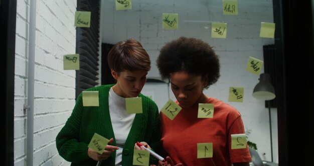 A diverse team participating in a brainstorming session. They are using sticky notes on a whiteboard to visualize ideas and strategies for implementing a four-day work week. The atmosphere is collaborative and energetic.