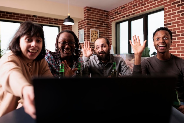 A diverse group of people smiling and interacting inside a virtual meeting room, each represented by their personalized avatars. The backdrop displays corporate branding, and there are interactive whiteboards and 3D models floating in the space.