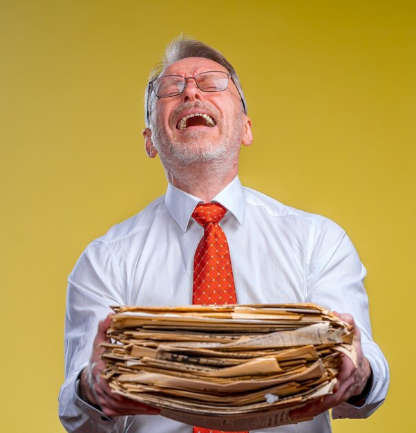 A manager handing a stack of papers to an employee who looks surprised and overwhelmed. The manager is smiling, while the employee's expression conveys stress.
