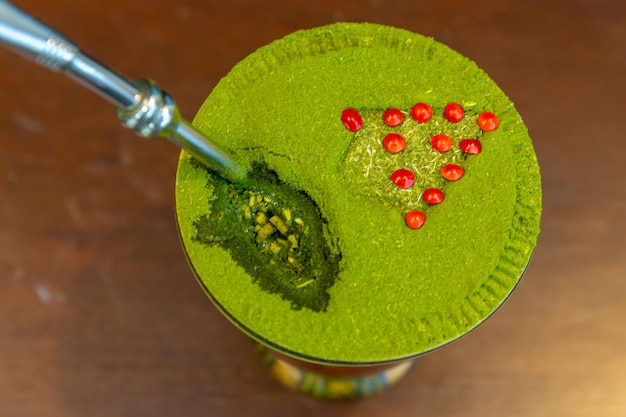A vibrant green moringa powder being sprinkled over a smoothie bowl filled with fruits, seeds, and nuts, with fresh moringa leaves placed on the side.
