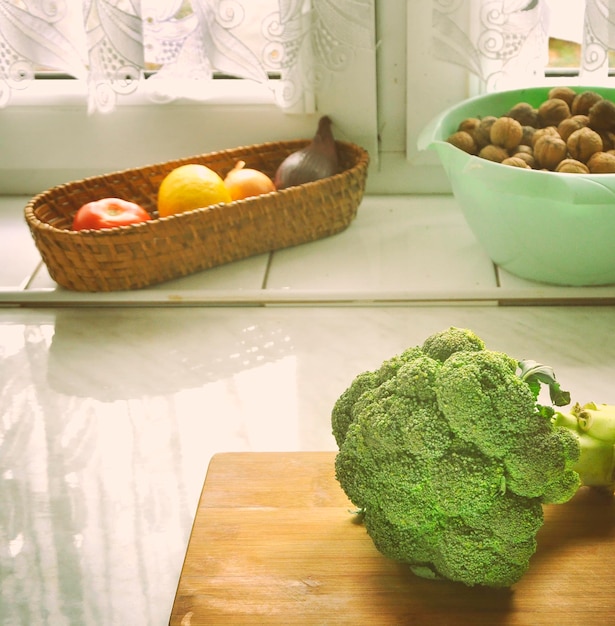 A modern kitchen scene with various healthy ingredients on the counter: fresh vegetables, fruits, nuts, and whole grains. A person is preparing a meal, emphasizing the practicality and ease of incorporating healthy food into daily life.