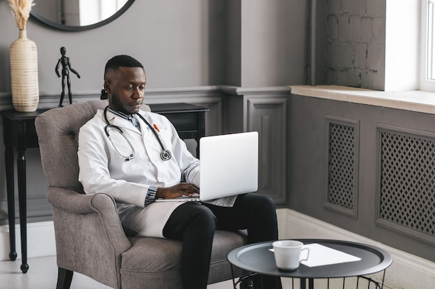 An image of a doctor in a white coat conducting a remote consultation with a patient via a tablet. The patient is in their home, looking comfortable as they discuss their health concerns. The background shows a cozy living room, emphasizing accessibility and convenience.