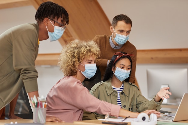 An office environment with people wearing masks and some employees at their desks, illustrating the context of workplace vaccine mandates and safety measures.