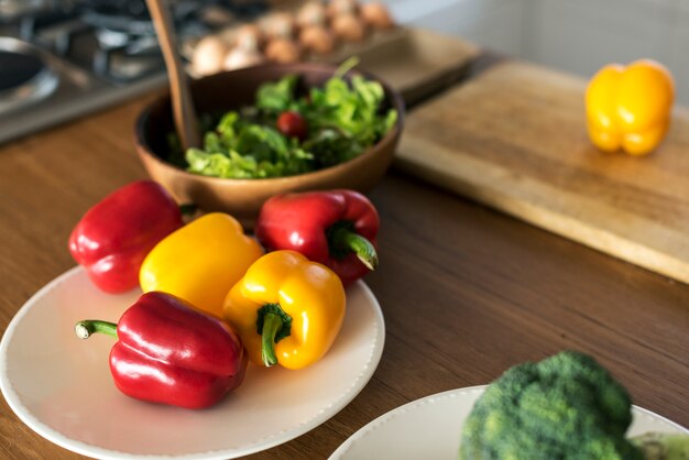 A close-up shot of a diverse selection of colorful vegetables being prepared in a kitchen. The image focuses on hands chopping the vegetables on a wooden cutting board, conveying a sense of freshness, health, and the process of cooking plant-based meals.