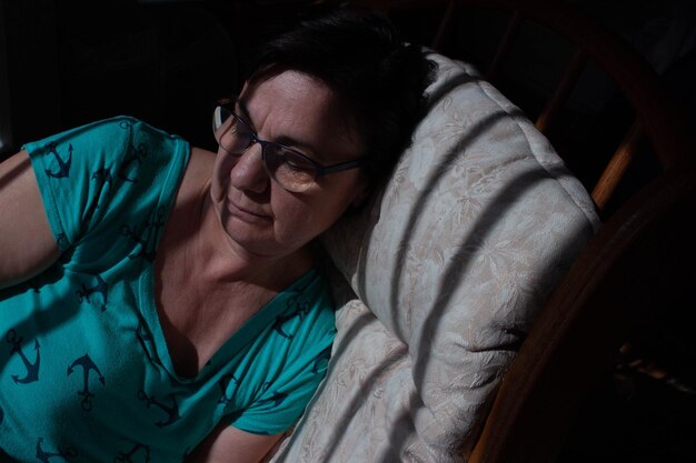 A close-up shot of a tired nurse sitting alone in a dimly lit break room, her head in her hands. The scene is meant to evoke feelings of exhaustion, overwhelm, and the emotional toll of working long hours under stressful conditions due to staffing shortages.