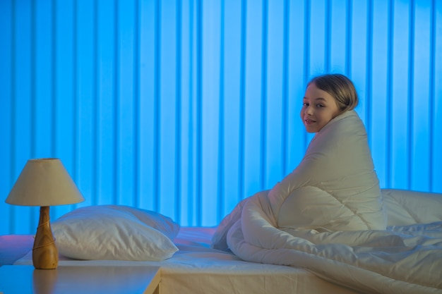 A dimly lit bedroom with blackout curtains, a comfortable bed, and a white noise machine on the nightstand, creating a serene and sleep-conducive environment.