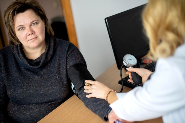 A close-up shot of a doctor explaining blood pressure readings to a senior patient. The doctor is pointing to a chart with blood pressure ranges, and the patient is listening attentively with a concerned expression.