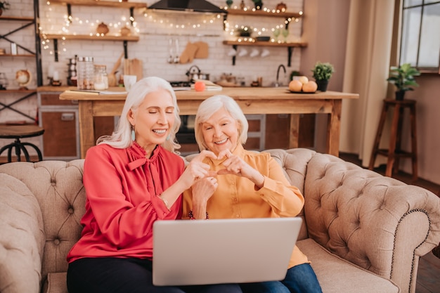 Two senior women working together on a jigsaw puzzle, smiling and focused, in a cozy living room setting.