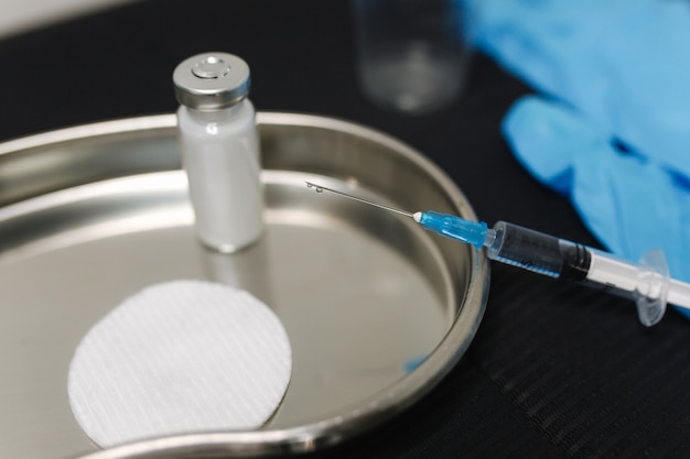 A close-up shot of a healthcare professional preparing a flu vaccine injection, with vials of different vaccine types and a syringe on a sterile tray.