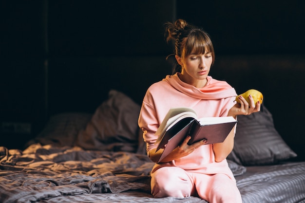 A person practicing a relaxing bedtime routine, such as reading a book in bed with soft lighting, drinking herbal tea, or meditating. The setting is a cozy bedroom with calming colors and minimal distractions.