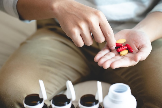 A close-up of a hand holding various vitamin supplements with a pill bottle, emphasizing the importance of proper dosage and consultation with a healthcare professional.