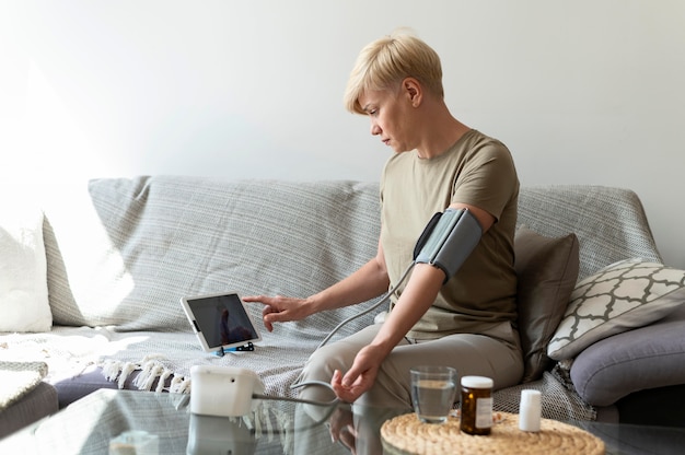A person using a blood pressure monitor at home, showing a reading within a healthy range. The background includes a clean and organized living space.