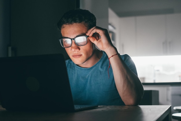 A person using blue light blocking glasses in front of a computer screen, demonstrating a method for reducing exposure and mitigating the potential risks to the eyes.