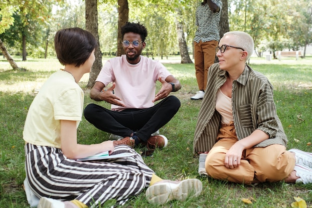 A diverse group of people laughing and talking together in a park, symbolizing social connection, support, and community.