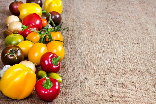 A close-up shot of a colorful assortment of fresh vegetables and fruits, including tomatoes, cucumbers, bell peppers, oranges, and grapes, arranged on a wooden table.