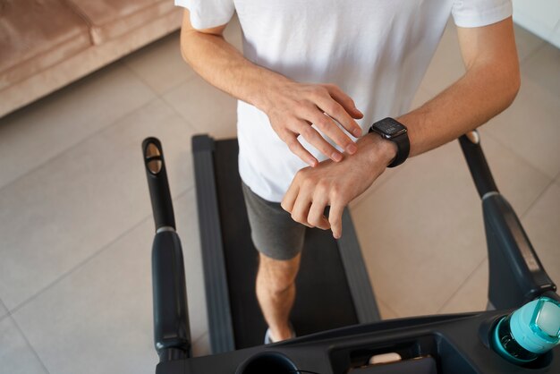 A person using a treadmill, with a visible fitness tracker on their wrist displaying calorie burn information. The image emphasizes the role of exercise in increasing daily calorie expenditure.