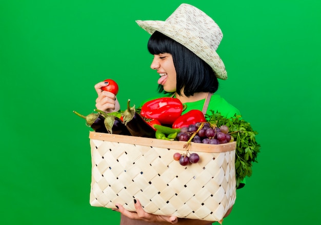 A person pushing a shopping cart filled with fresh produce, including leafy greens, colorful bell peppers, and a variety of fruits. The person is checking a shopping list on their smartphone, ensuring they stick to their planned meal prep ingredients.