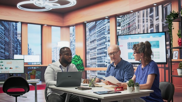 A diverse group of healthcare professionals discussing telehealth regulations around a table in a modern office setting, with laptops and documents spread out.