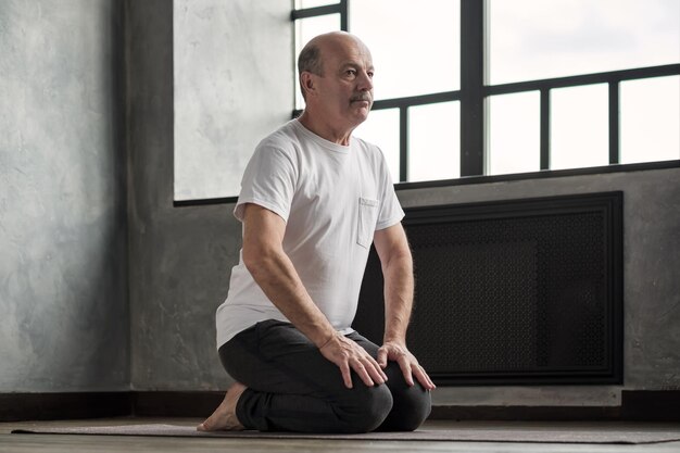 A senior man doing a wall sit with proper form, demonstrating a safe and effective strength training exercise that can be done at home to improve lower body strength.