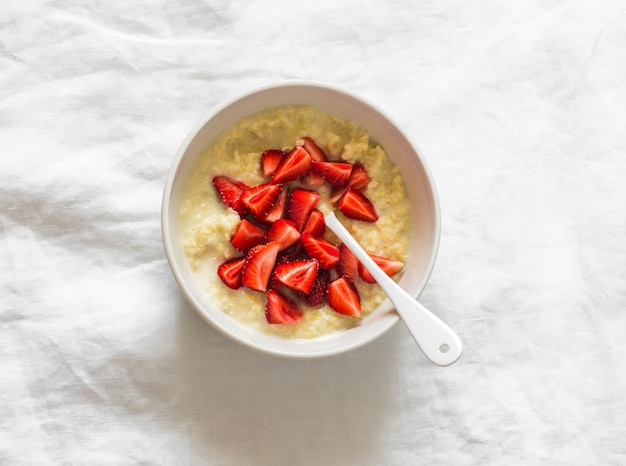 A close-up, overhead shot of a bowl of creamy oatmeal topped with fresh berries (strawberries, blueberries, raspberries), chopped nuts (almonds, walnuts), and a drizzle of honey, highlighting the texture and colors of the ingredients. The bowl is placed on a light-colored wooden surface with a spoon resting beside it, creating a visually appealing and inviting image of a healthy breakfast.