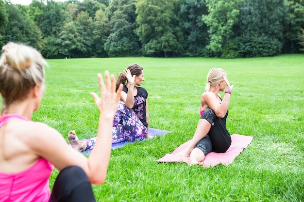 A serene outdoor yoga class in a park setting, with participants practicing poses and focusing on their breath. The atmosphere is peaceful and encouraging to promote wellbeing with physical and mental practices.